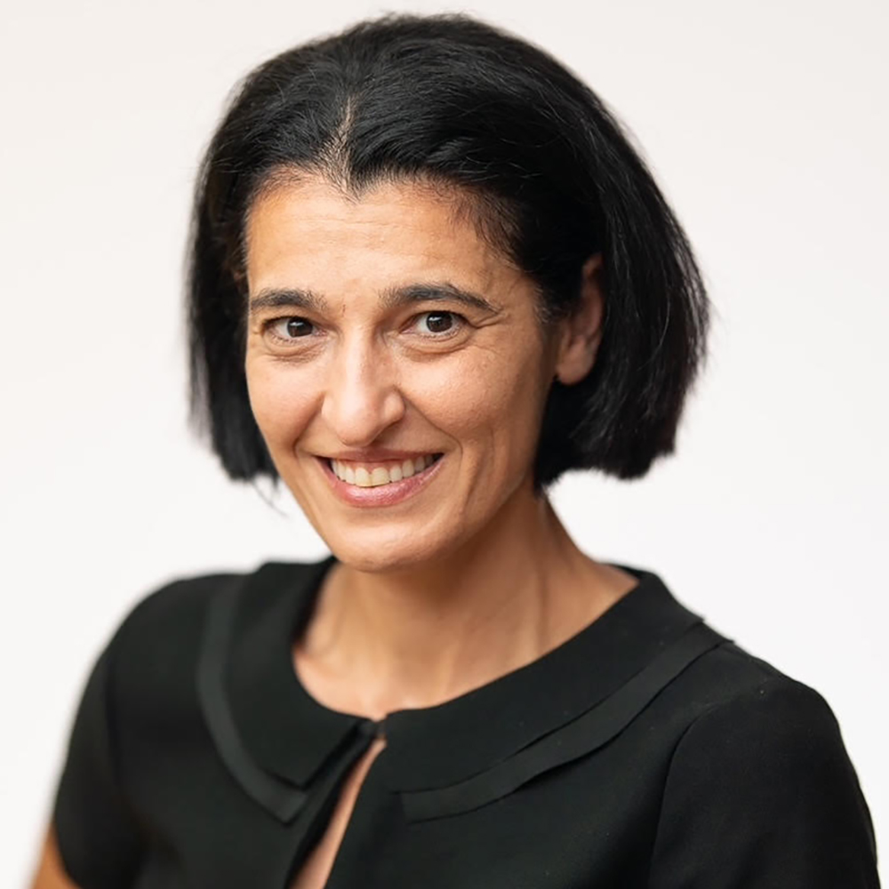 A dark hiared woman with a bob in a black top from the shoulders up smiles at the camera.